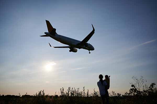 silhouette of woman with child looking at landing aeroplane